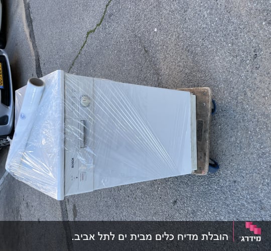 מכונת כביסה עטופה בניילון על עגלת הובלה